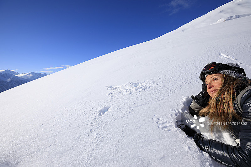 业余爱好者冬季运动高山滑雪：雪地女子在滑雪胜地滑雪图片素材