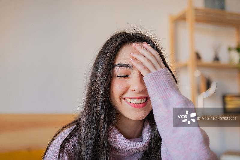 闭着眼睛用手遮住脸的深色长发年轻女子肖像图片素材