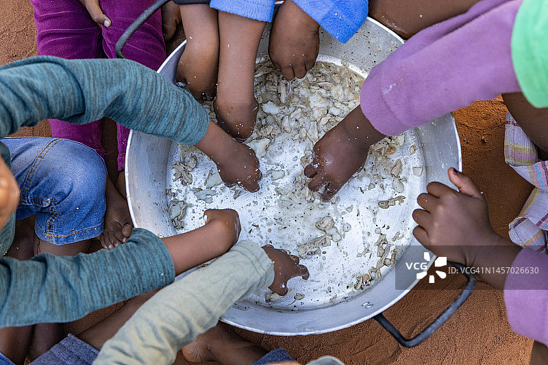 非洲的贫困：一群饥饿的非洲儿童从公共锅底刮食物图片素材