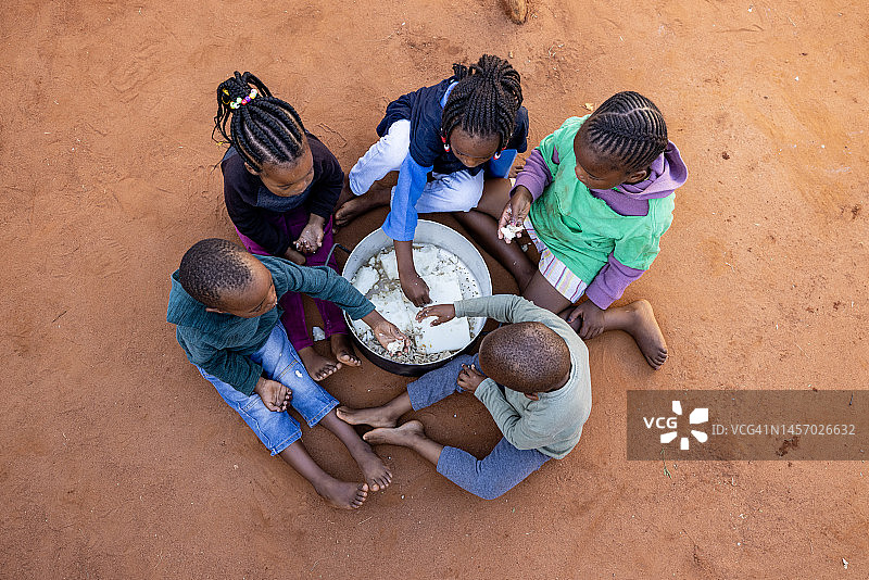 非洲的贫困：一群饥饿的非洲儿童分享玉米粥图片素材