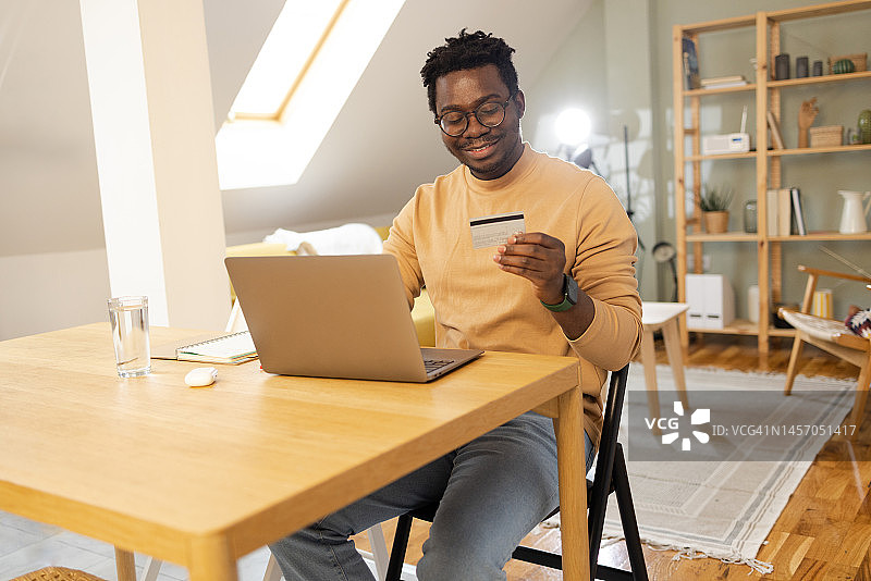 年轻的非裔美国人在家进行在线支付。图片素材