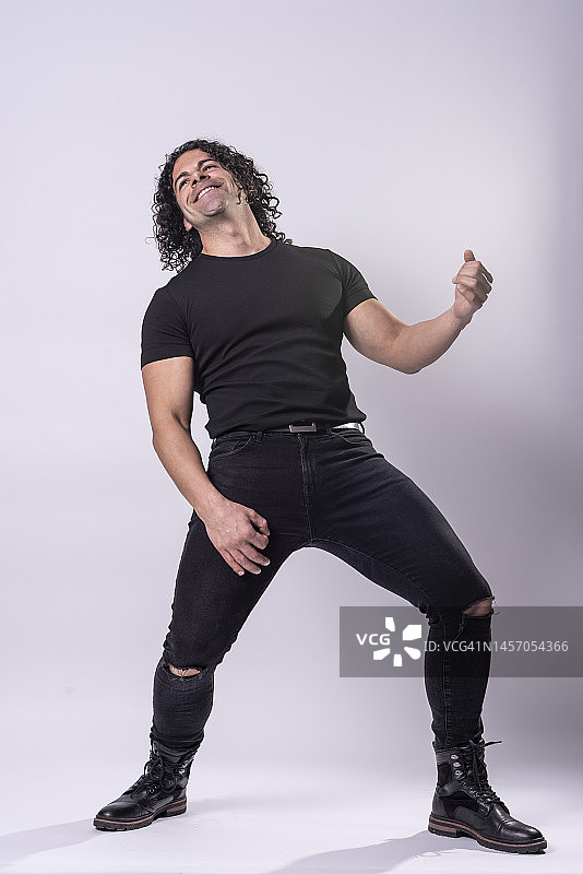 在白色工作室背景下练习空气吉他的西班牙多毛男人肖像图片素材