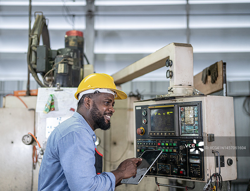 非裔美国男程序员在自动化数控机床前输入数据图片素材