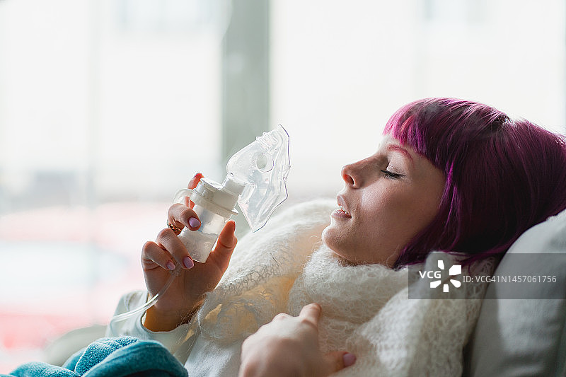 流感和感冒季：在家用雾化器面罩吸入药物的妇女图片素材