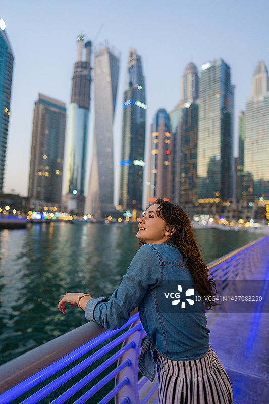 日落时分在迪拜码头散步的女人图片素材