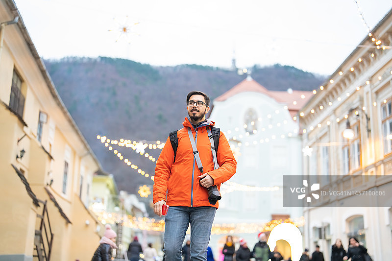 旅行者在城镇中行走，携带数码相机和手机图片素材
