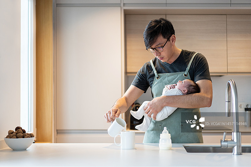 在日本厨房，男子用奶瓶喂新生儿图片素材
