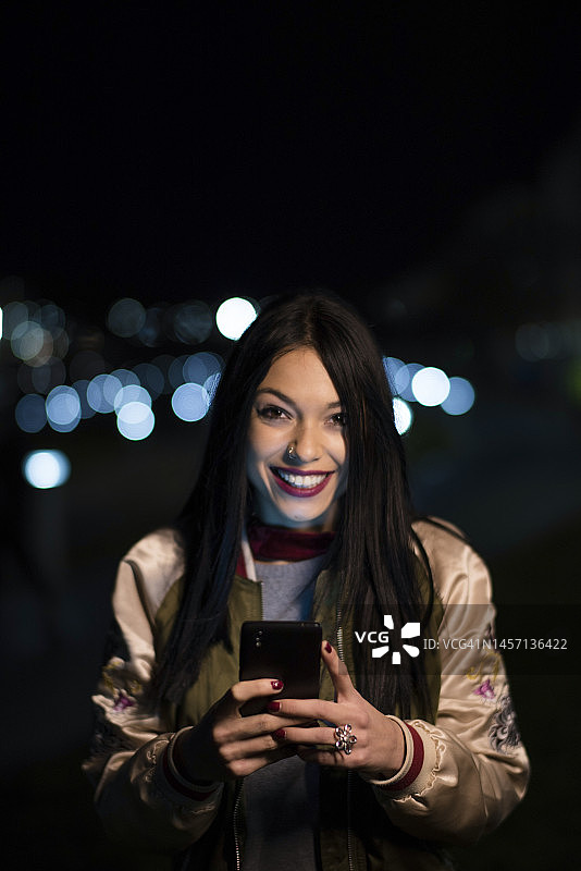 夜晚在城市里看手机的女人图片素材