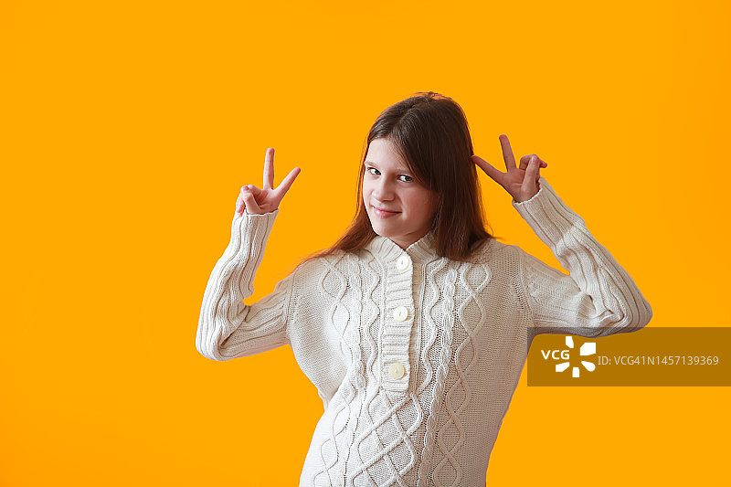 穿着针织保暖外套，比出胜利手势的少女图片素材