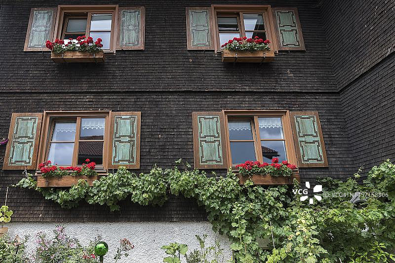 巴伐利亚阿尔高地区的房屋，带有木瓦外墙、百叶窗和花箱图片素材