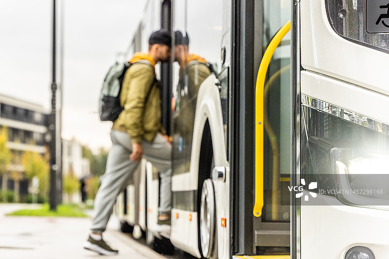 男人登上公共汽车，焦点对准公共交通保险杠侧面图片素材