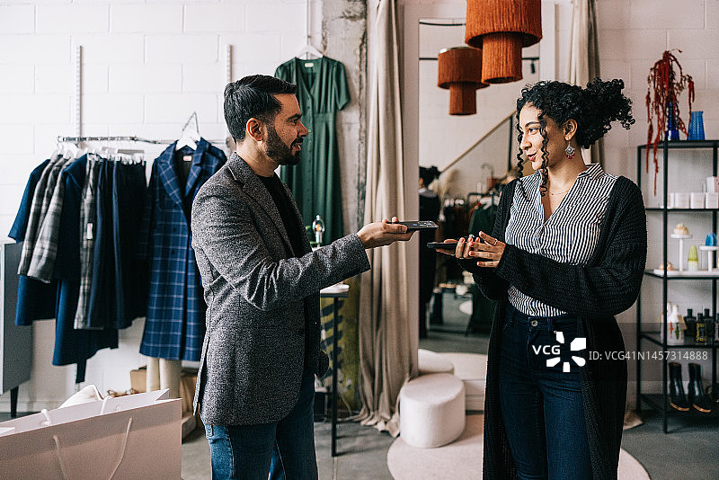 印度商人在精品店使用手机支付图片素材