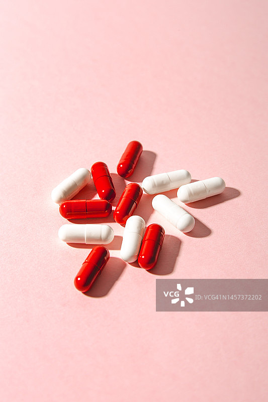 具有强烈光影效果的红白胶囊药丸，保健维生素和益生元图片素材