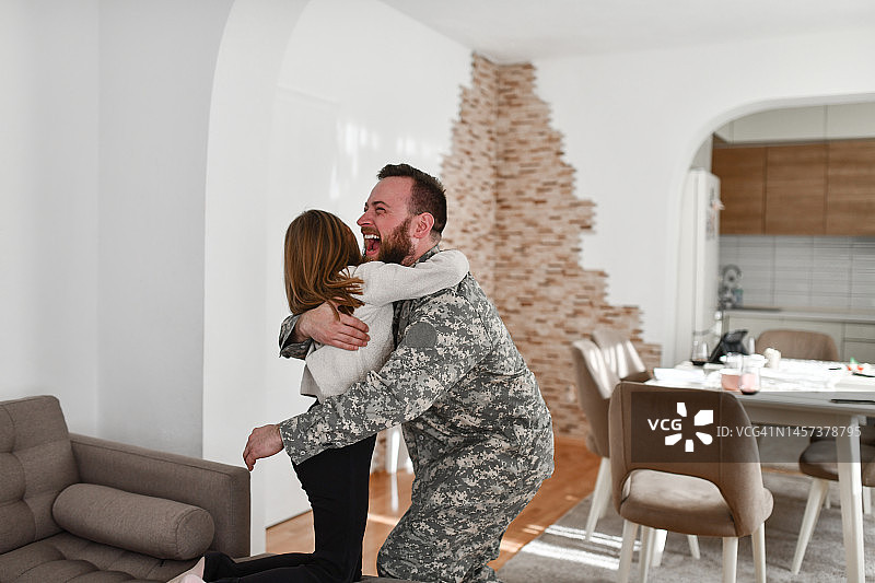 很久没见女儿后，拥抱小女儿的兴奋的男士兵图片素材