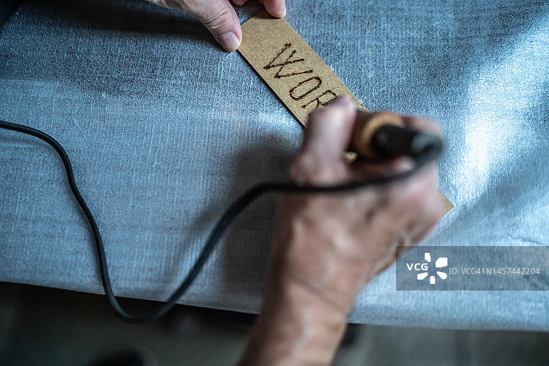 在家用热烙笔在木板上写字的男士面部特写图片素材