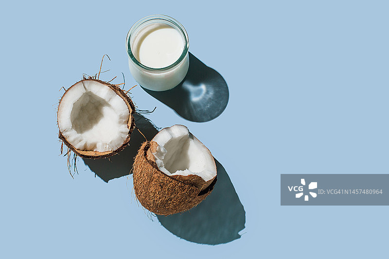 蓝色背景上的成熟椰子和有机纯素椰奶图片素材
