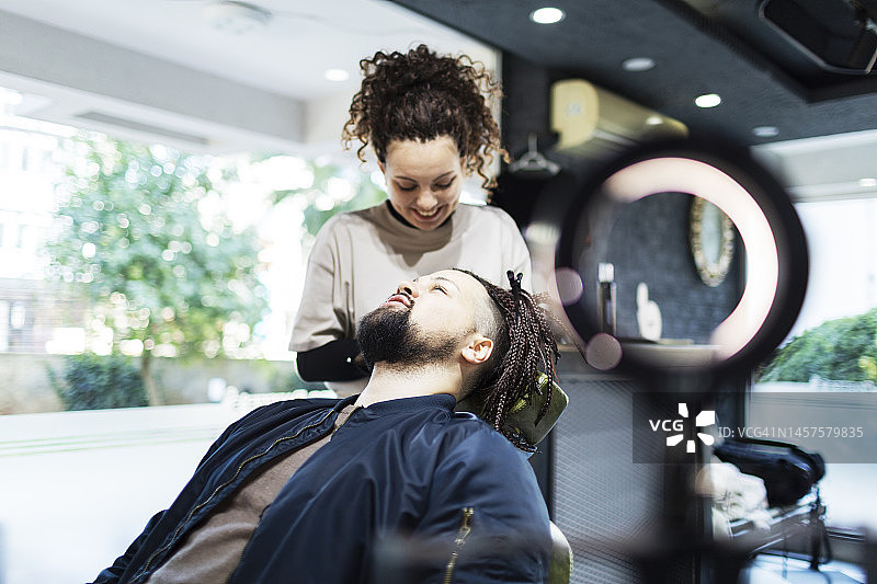 年轻女理发师在理发店为顾客编发图片素材