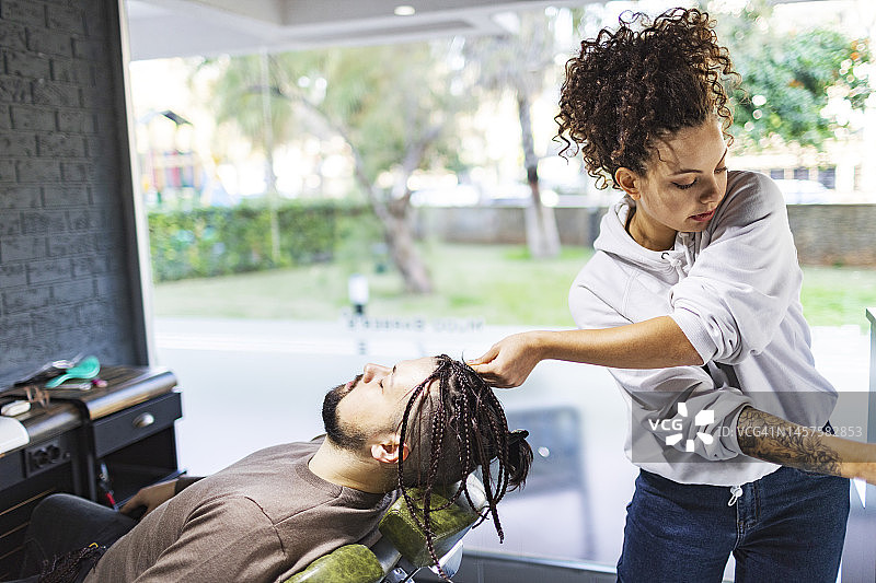 年轻女理发师在理发店为顾客编发图片素材