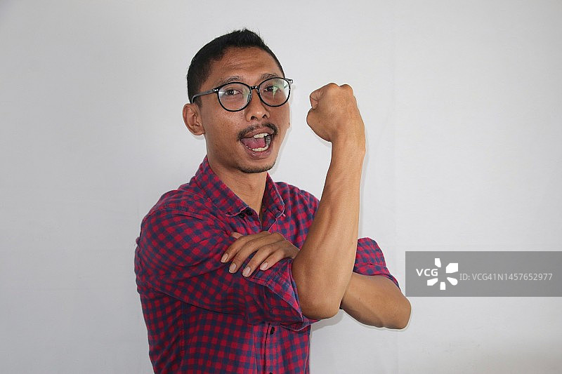 兴奋的亚洲男人展示强壮的姿势，举起手臂和肌肉图片素材