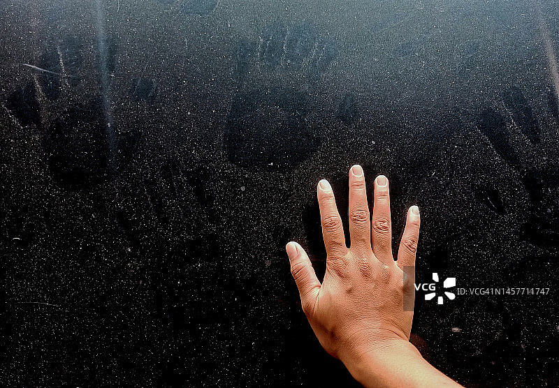 一只手放在玻璃上，尘土中有一个手印图片素材