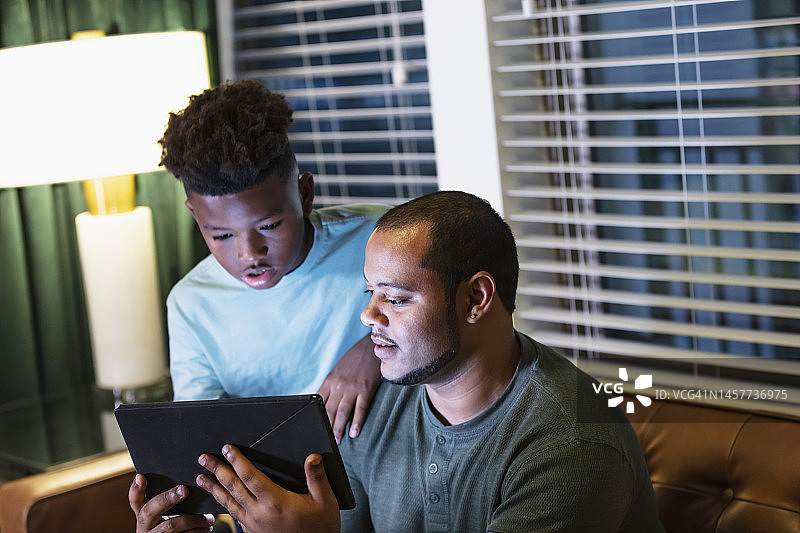 多种族父亲和继子观看平板电脑图片素材
