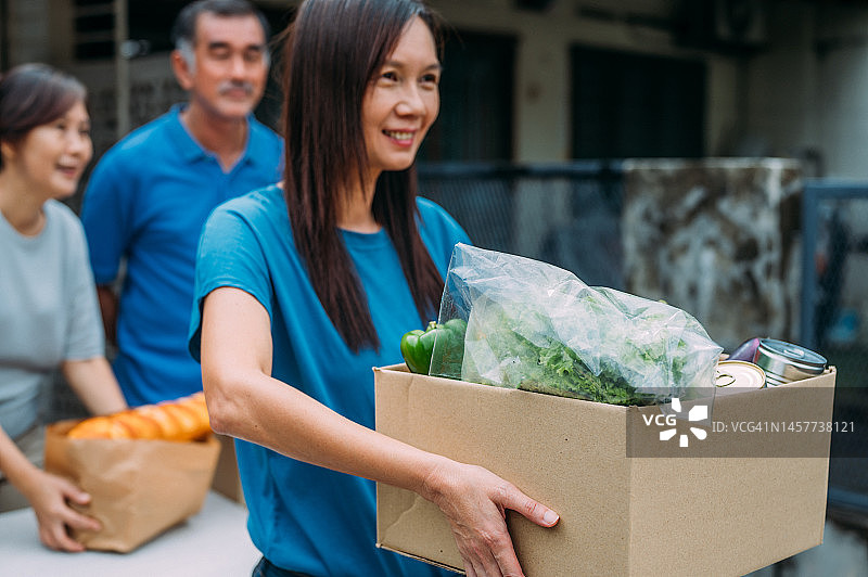 微笑的亚洲女性志愿者在社区食品银行分发食品图片素材