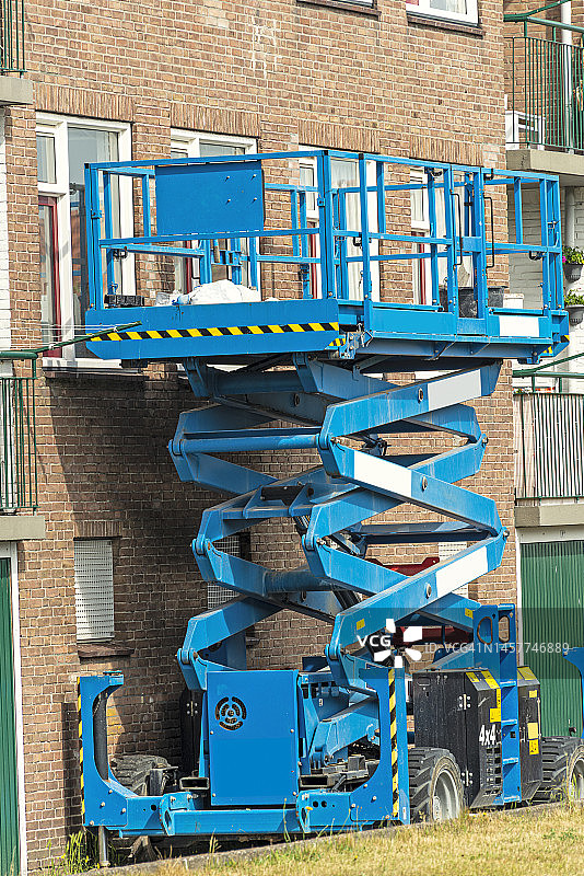 公寓楼前的蓝色剪叉式升降平台图片素材