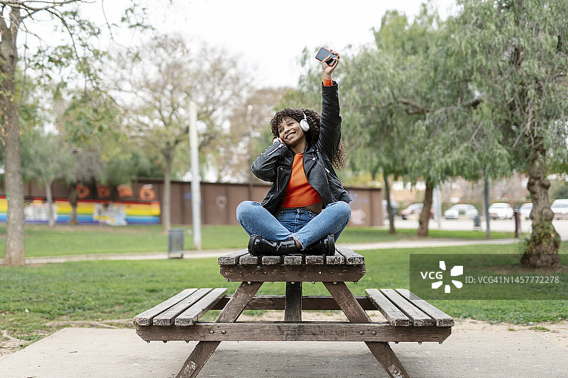 年轻黑人女人戴耳机公园听音乐图片素材