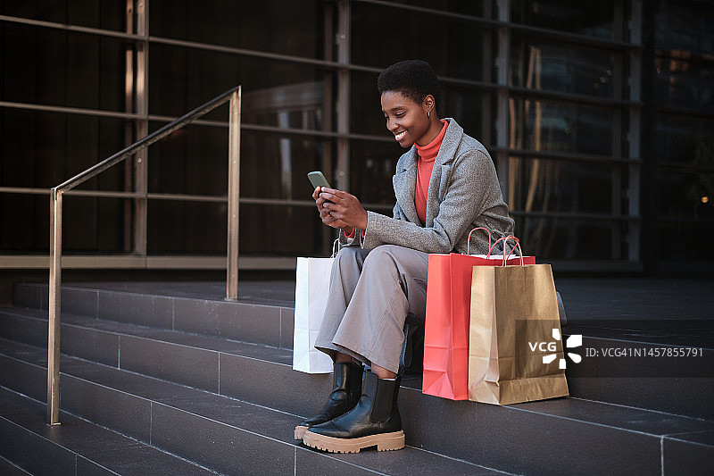 坐在购物袋旁使用手机的女人图片素材