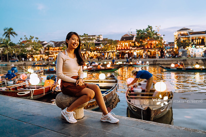 女人坐在越南会安的河边长廊上图片素材