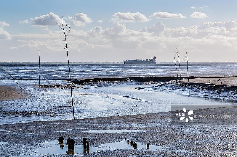 威悉河口的瓦登海潮汐小溪与集装箱船，德国下萨克森州图片素材