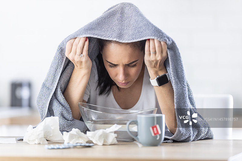 一名患感冒的妇女因鼻腔发炎而吸入热蒸汽。图片素材