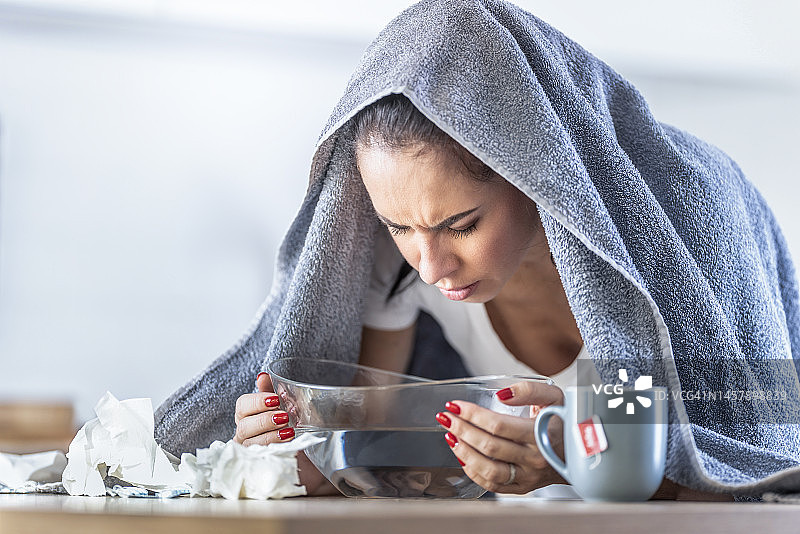 女人因呼吸道阻塞和鼻窦发炎而吸入热蒸汽图片素材