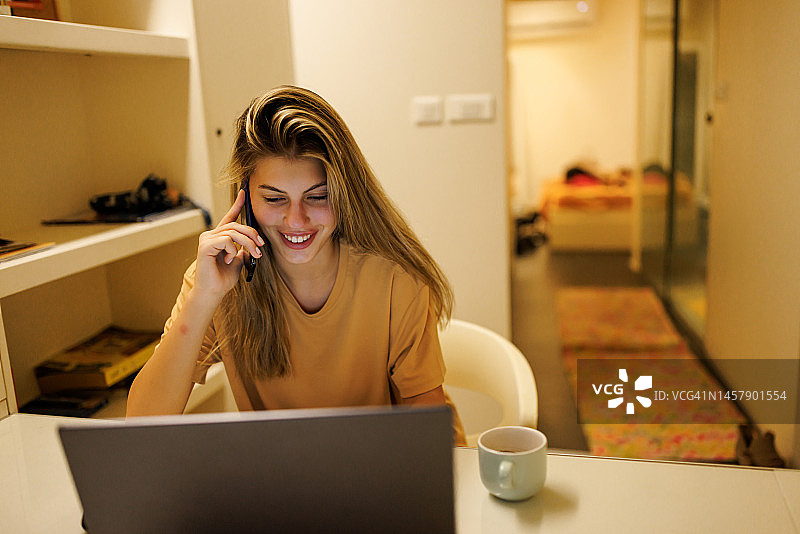 晚上在家使用笔记本电脑打电话的年轻女子图片素材