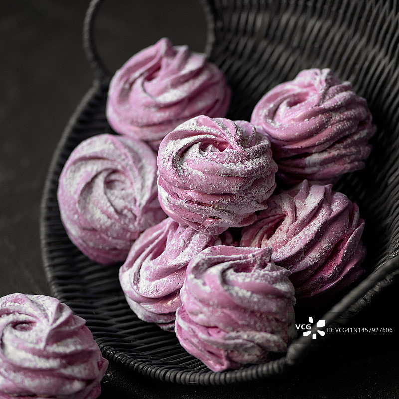 柳条筐里的自制苹果浆果棉花糖。棉花糖由琼脂、水果和浆果泥制成，并裹有糖粉。深色背景，特写图片素材