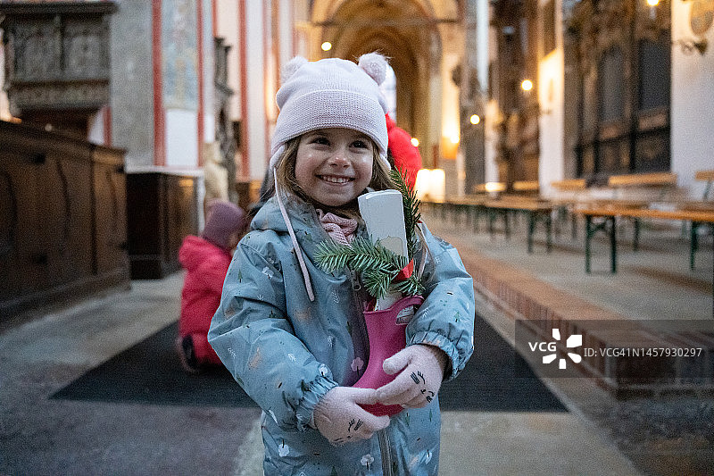 在教堂里拿着装有巧克力和槲寄生靴子的白人幼儿女孩图片素材