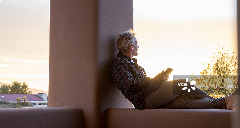 男人在日出时分于家中阳台放松图片素材