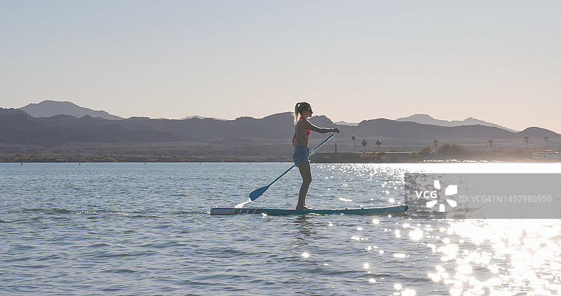 女子在平静的湖面上划桨板（SUP）图片素材