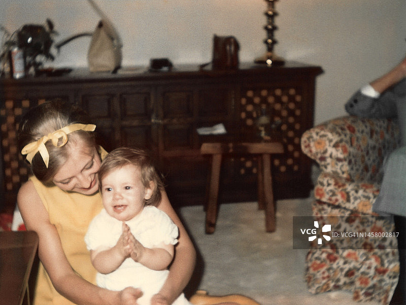 1967年，年轻母亲教蹒跚学步的孩子拍手的复古照片图片素材