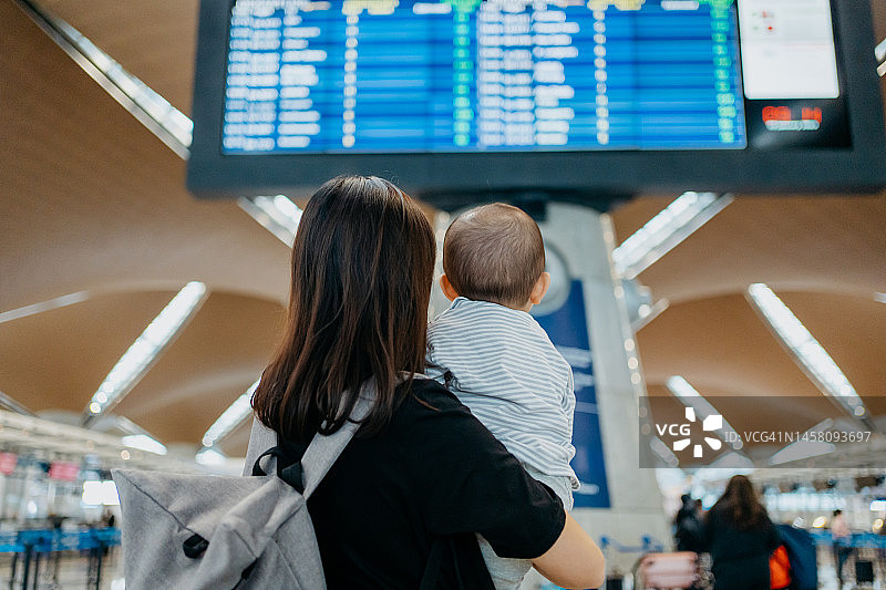 母亲和婴儿在机场看航班信息显示屏图片素材