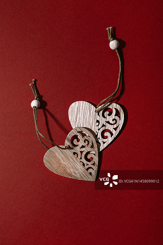 红色背景上的木制爱心，情人节创意极简概念图片素材
