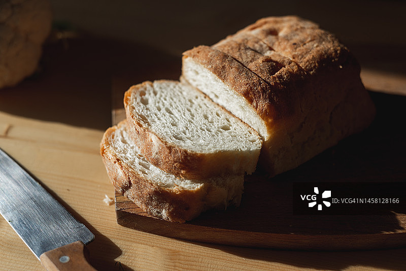 厨房里阳光下木板上的切片软质新鲜面包图片素材