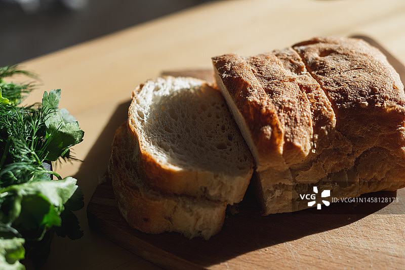 厨房里阳光下木板上的切片软质新鲜面包图片素材