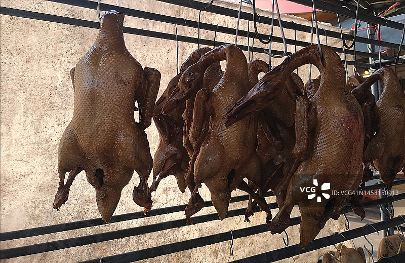 市场铁栏杆上悬挂的红烧鸭图片素材