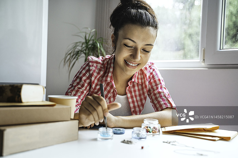 漂亮女孩在家制作宝石首饰。艺术、爱好、手工概念。图片素材