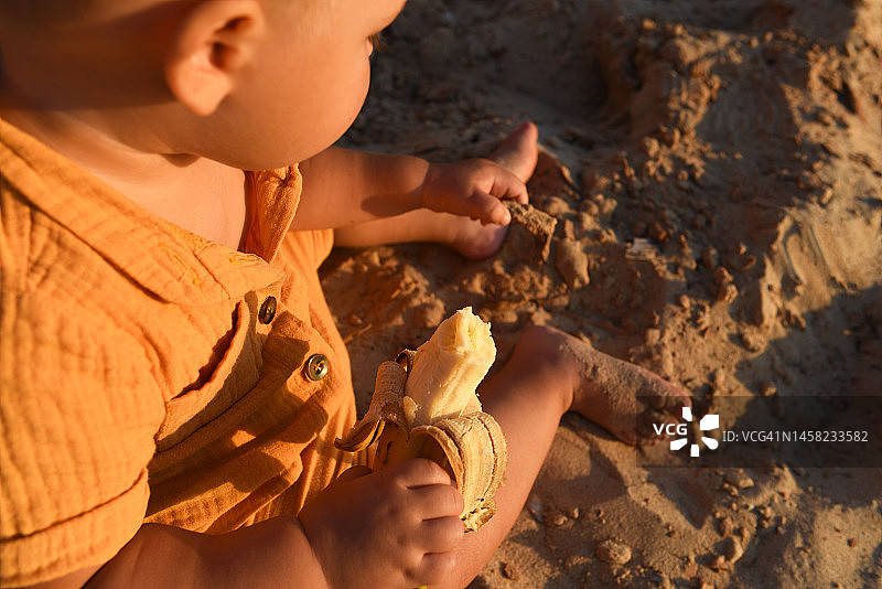 小男孩在沙滩上吃香蕉，户外休闲图片素材