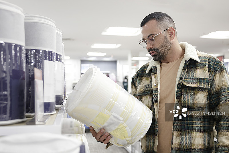 戴着眼镜和格子夹克的拉丁裔千禧年男人在百货商店购物图片素材