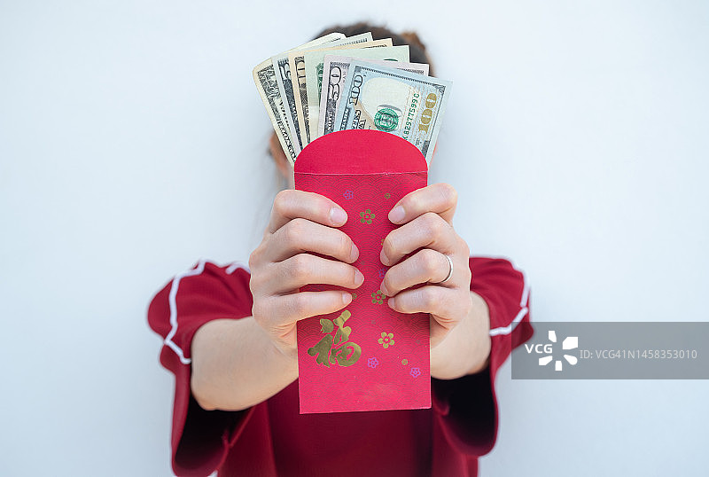女子手持装有美元的红包，在中国文化中，红色象征着活力、幸福和好运图片素材