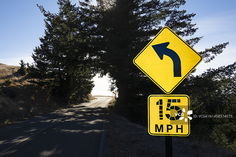 带有速度限制标志和箭头的弯曲道路图片素材