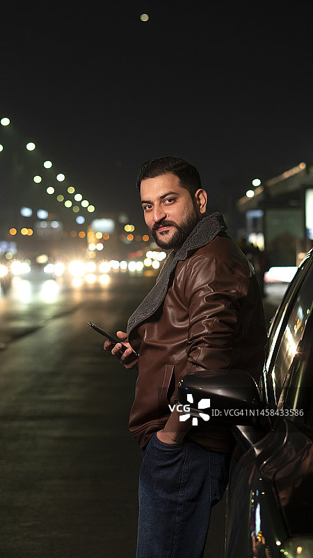 晚上站在路边汽车旁的年轻男人图片素材